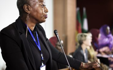 A Middle African Descent Woman Speaking into a Microphone